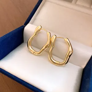 Nahaufnahme unregelmäßiger welliger goldener Creolen in einer blauen Schmuckschatulle