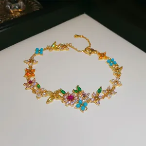 Macro detail of luxury 18k gold plated bracelet featuring vibrant colorful zircon flower motifs