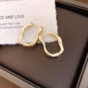 Detailansicht von unregelmäßigen goldenen Creolen mit glattem Plissee-Finish für Damen.