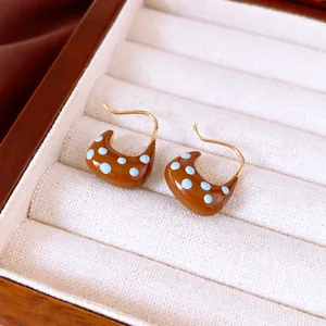 Vue détaillée des boucles d'oreilles en émail marron doré 18 carats à pois bleu clair.