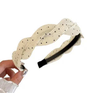 Elegante diadema trenzada de tela crema con lunares negros para un efecto de volumen