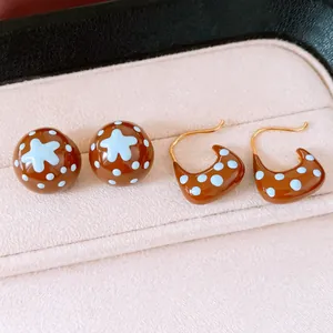 Vue détaillée de boucles d'oreilles en émail marron plaqué or 18 carats à pois bleus