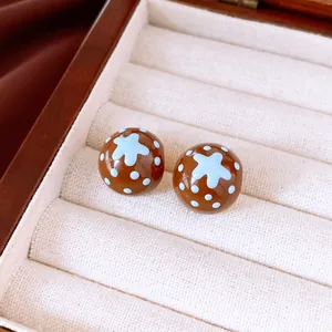 Gros plan de boucles d'oreilles marron à pois bleus et motif d'étoile dans un coffret