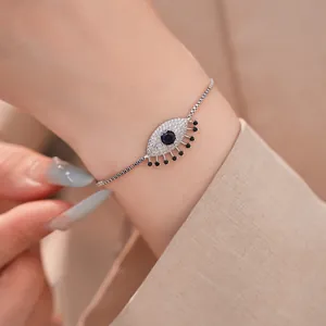 Λεπτομέρεια ασημένιου βραχιολιού evil eye με γαλάζια και διαφανή ζιργκόν στον καρπό.