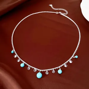 Detailed silver necklace with turquoise beads and clear zircons on brown satin background