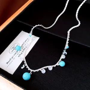 Close-up detail of silver-toned necklace with blue beads and sparkling zircon accents.