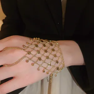 Detailed macro view of a gold mesh hand chain jewelry with integrated rings and tassels