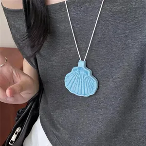 Detail van de blauwe schelphanger ketting gedragen door model voor strandstijl