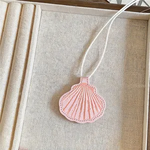 Detailopname van een roze schelpvormige lederen hanger ketting in een sieradenbakje.