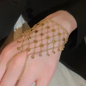Detail view of an intricate gold mesh hand harness with sunburst metal discs and tassels.