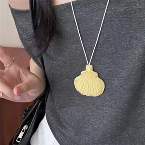 Close-up van een stijlvolle gele leren schelphanger ketting gedragen op een grijs t-shirt