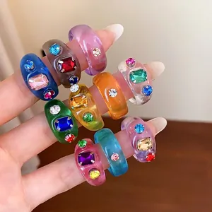 Lebhafte bunte Harzringe im koreanischen Stil mit eingelegten Strasssteinen auf der Hand.