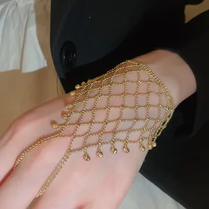 Close-up detail of an exquisite gold hollow mesh hand chain with delicate tassel drops