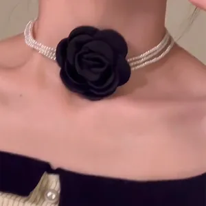 Detailansicht eines eleganten mehrreihigen Perlen-Chokers mit einer großen schwarzen Stoffrose.