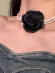 Nahaufnahme eines mehrlagigen Perlen-Chokers mit einer großen schwarzen Stoffblume Detail.