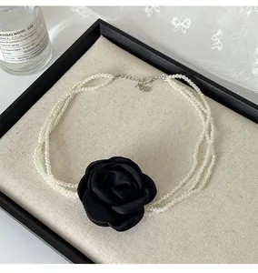 Detailansicht eines mehrreihigen Perlen-Chokers mit handgefertigter schwarzer Stoffrose.