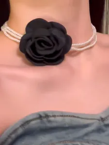 Detailansicht eines mehrlagigen Perlen-Chokers mit einer großen schwarzen Stoffrose.