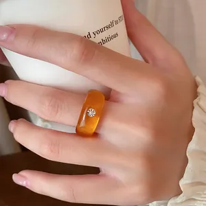 Detailansicht eines minimalistischen bernsteinfarbenen Harzrings mit Kristall