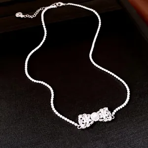 Élégant collier argenté avec pendentif nœud orné de zircons et d'une perle centrale raffinée