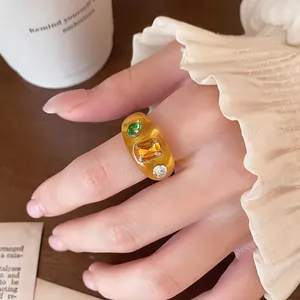 Nahaufnahme eines bernsteinfarbenen Harzrings im Vintage-Stil mit bunten Edelsteinen