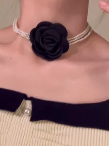 Detailansicht einer mehrlagigen Perlen-Choker-Halskette mit einer schwarzen Stoffrose