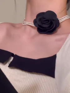 Detailansicht eines mehrreihigen Perlen-Chokers mit einer großen schwarzen Stoffrose.