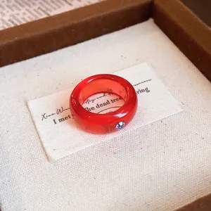 Nahaufnahme eines roten Harzrings mit lila Strassstein in einer Geschenkbox