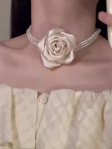 Nahaufnahme eines eleganten mehrlagigen Perlen-Chokers mit einer großen cremefarbenen Stoffrose