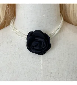 Detailansicht einer eleganten mehrlagigen Perlenkette mit einer schwarzen Stoffblume