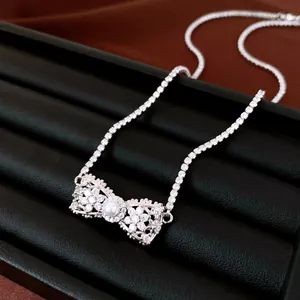 Gros plan d'un collier pendentif nœud élégant en zircon avec perle sur support noir