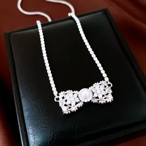 Vue détaillée d'un collier en forme de nœud argenté avec zircons et perle centrale