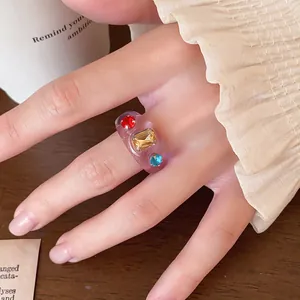 Detailansicht eines lila Harzrings mit bunten Strasssteinen an einem Finger getragen