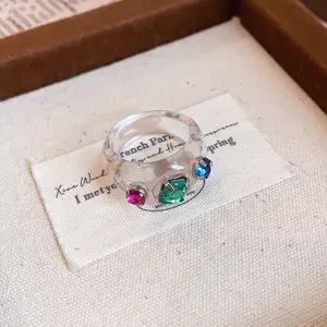 Nahaufnahme eines transparenten Harzrings mit bunten, funkelnden Strasssteinen-Detail.
