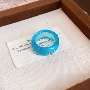 Detaillierte Makroansicht eines blauen Harzrings mit einem rosa Kristallakzent.