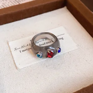 Detailaufnahme eines grauen Harzrings mit bunten Kristallen in einer Geschenkbox