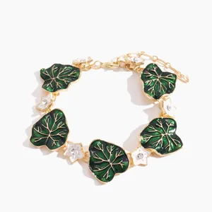 Vintage gold bracelet with green enamel leaves and white rhinestone flower charms