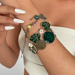 Detailed view of a vintage-style enamel bracelet featuring green leaves and white flowers.