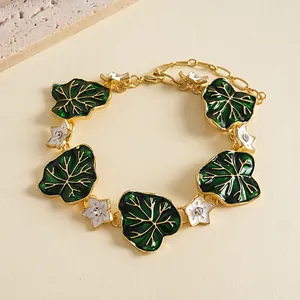 Detailed view of vintage green leaf and white flower charms on a gold bracelet