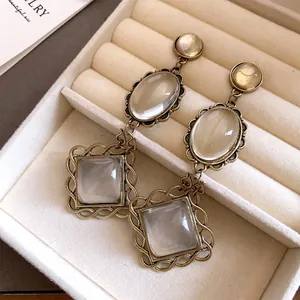 Gros plan de boucles d'oreilles vintage en or antique avec pierres claires dans un écrin.
