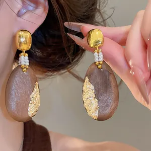 Primer plano de pendientes colgantes de madera de estilo étnico vintage con pan de oro