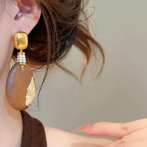 Primer plano detallado de pendientes étnicos de gota de madera con pan de oro vintage