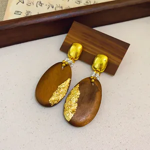 Vista detallada de pendientes étnicos de madera con pan de oro y cuentas elegantes