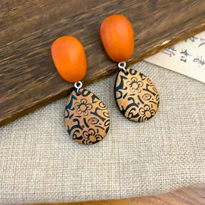 Primer plano detallado de pendientes étnicos de madera con patrón floral vintage.