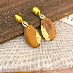 Primer plano que muestra la textura de pan de oro en pendientes étnicos de madera