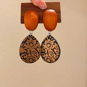 Primer plano de pendientes étnicos de madera con forma de gota y estampados florales retro