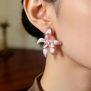 Nahaufnahme eines rosa Lilienblüten-Ohrsteckers mit Zirkon am Ohr des Trägers