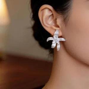 Detailaufnahme eines silbernen Blumenohrsteckers mit Zirkonia-Stein und feiner Textur
