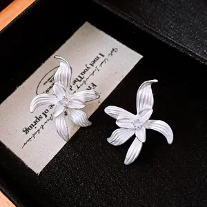 Detailaufnahme der eleganten silbernen Blumenohrstecker mit weißem Emaille-Finish