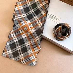 Eleganter karierter Schal in warmen Maillard-Tönen in einer rustikalen Holzschale Detail