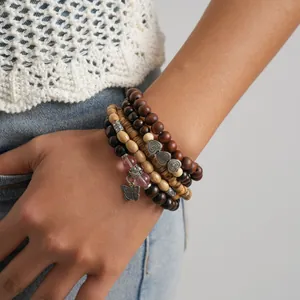 Detail view of 5-piece bohemian wooden beaded stretch bracelet set on wrist with charms